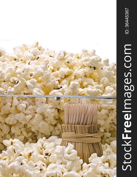 Wooden toothpicks in round wattled straw holder in popcorn. Wooden toothpicks in round wattled straw holder in popcorn