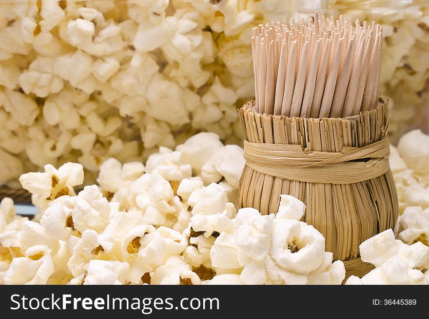 Wooden toothpicks in round wattled straw holder in popcorn. Wooden toothpicks in round wattled straw holder in popcorn