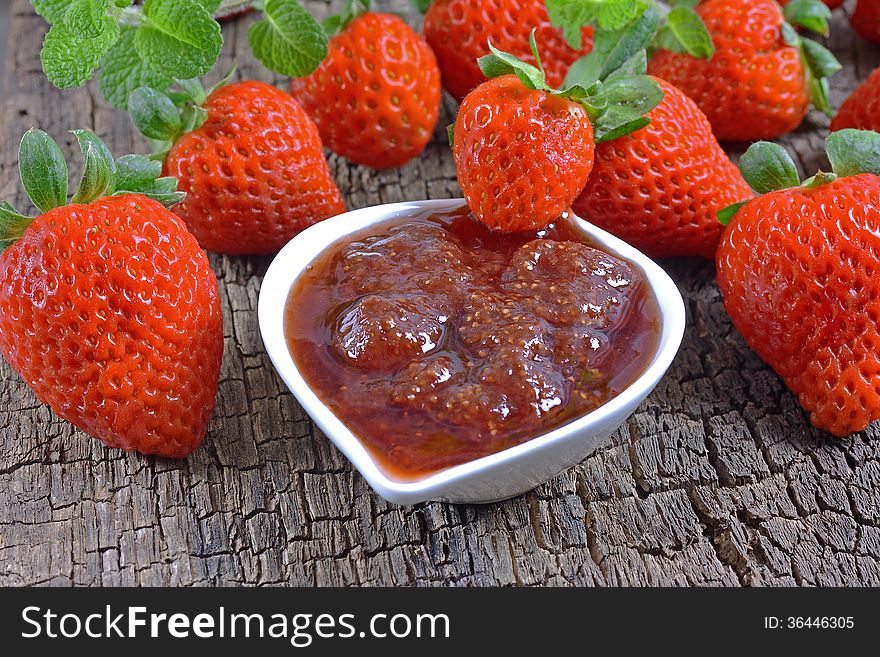 Strawberry jam and strawberry on a wooden surface