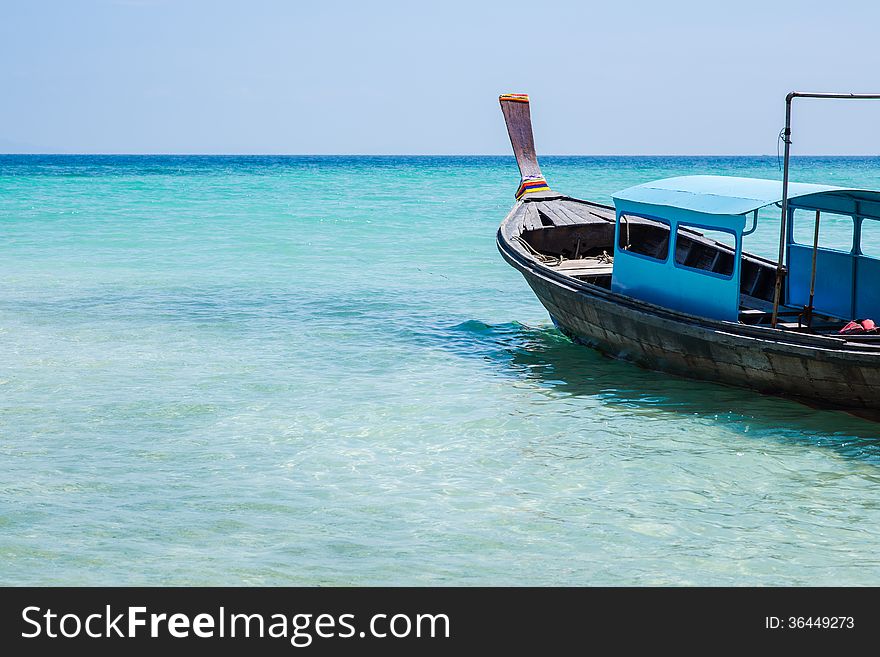 Blue boat on the beach in the transparent water