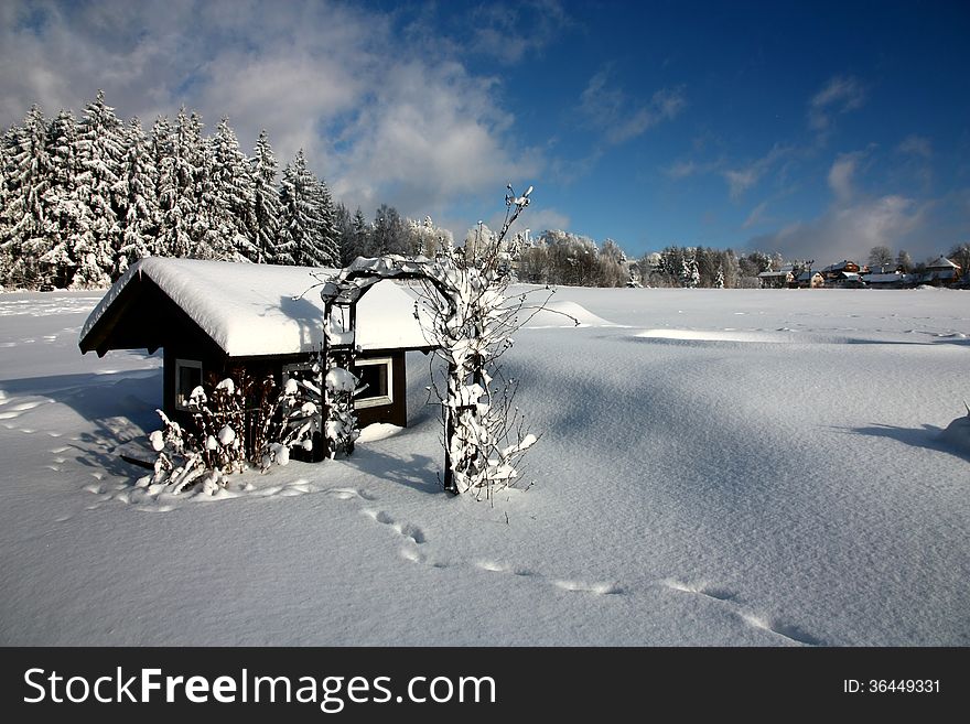 Snowy small wooden house, footprints in the snow. Snowy small wooden house, footprints in the snow