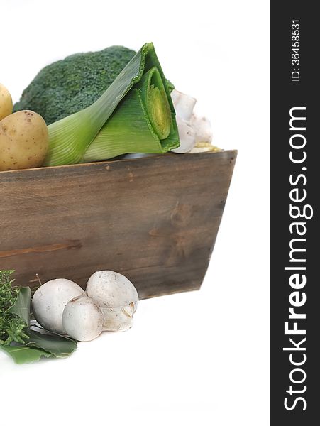 Different seasonal vegetables and mushrooms in wooden basket on white background