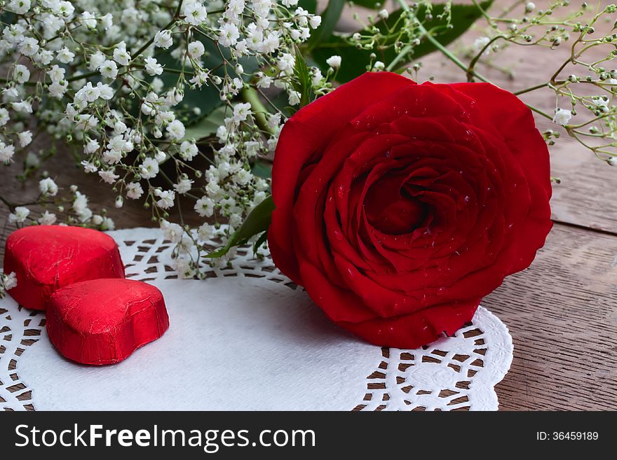 Red rose and chocolates wrapped in foil in the form of heart, as a greeting card