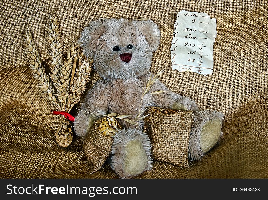 Stuffed teddy sitting on burlap with sacks of grain for sale. Stuffed teddy sitting on burlap with sacks of grain for sale.