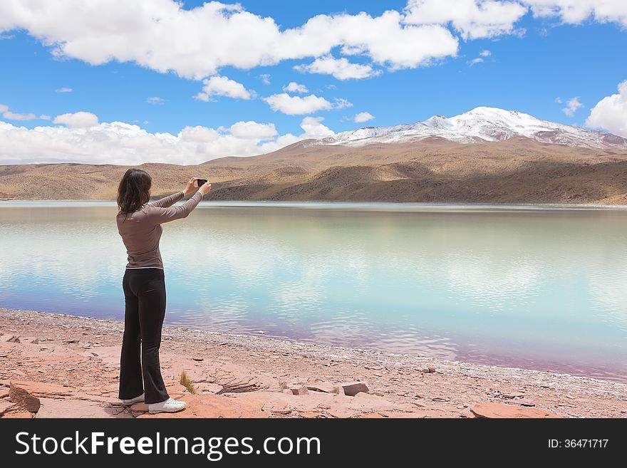 Woman taking pictures of lagoon Celeste, Bolivia on mobile phone. Woman taking pictures of lagoon Celeste, Bolivia on mobile phone