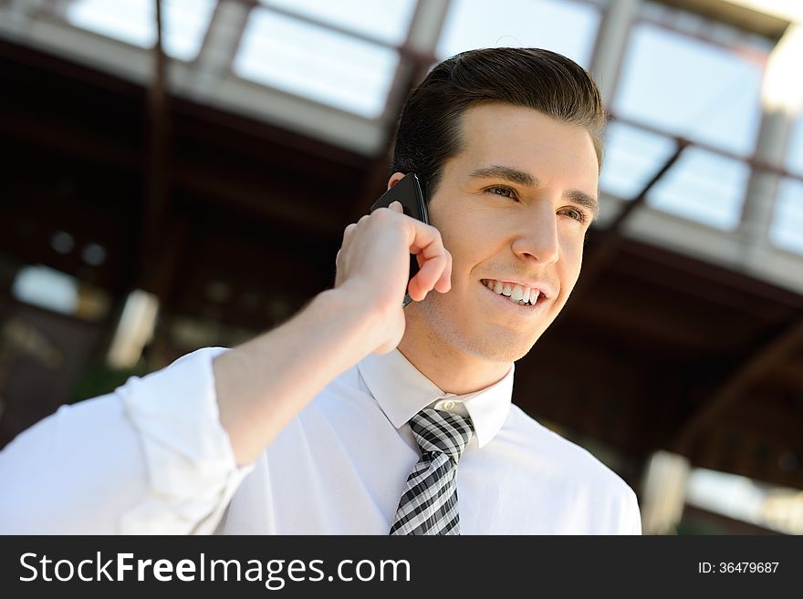 Portrait of an attractive businessman making a call using a smart phone in an office building. Portrait of an attractive businessman making a call using a smart phone in an office building