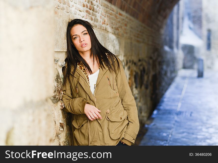 Portrait of brunette young woman with green eyes, wearing a coat, in urban background. Portrait of brunette young woman with green eyes, wearing a coat, in urban background