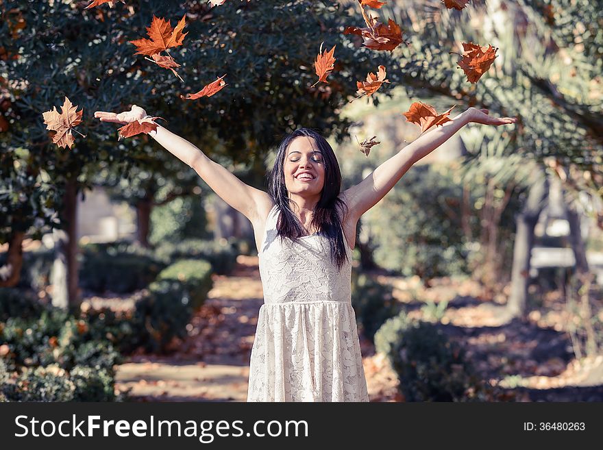 Portrait of beautiful brunette girl with falling leaves in the autumn