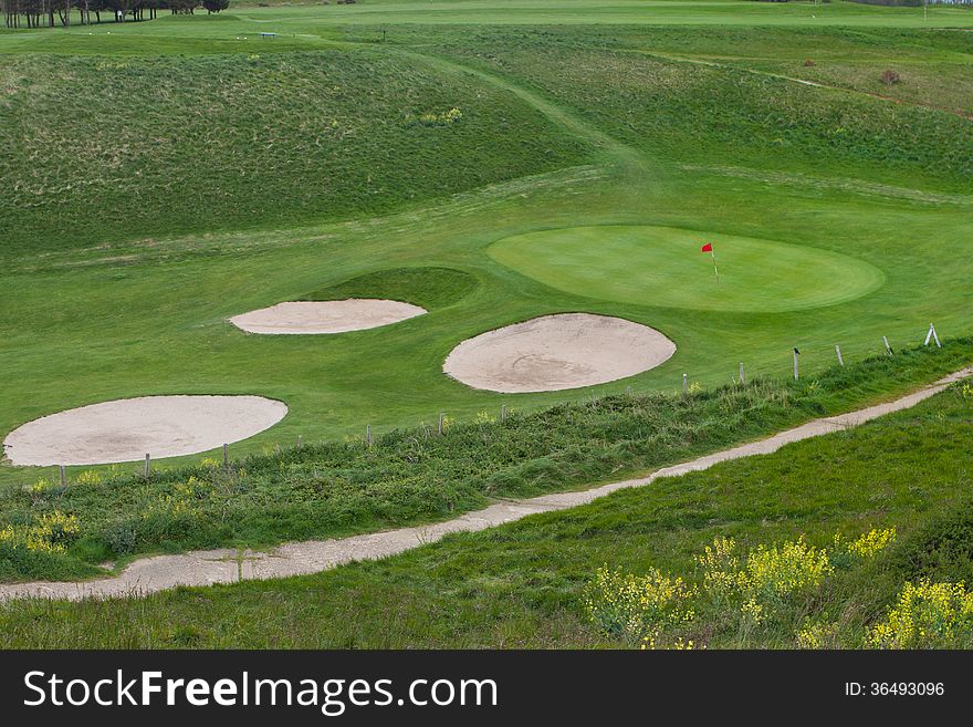 Wavy green golf field with a red flag