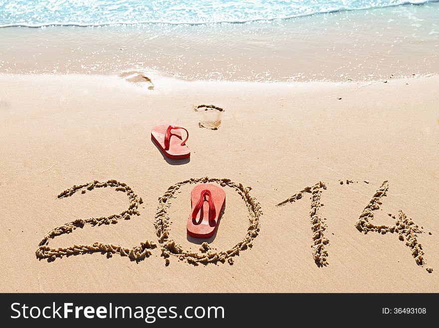 Red flip flops and digits 2014 on the beach sand.Concept of summer vacations and new year. Red flip flops and digits 2014 on the beach sand.Concept of summer vacations and new year