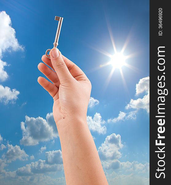 Hand holding key on sunny sky background