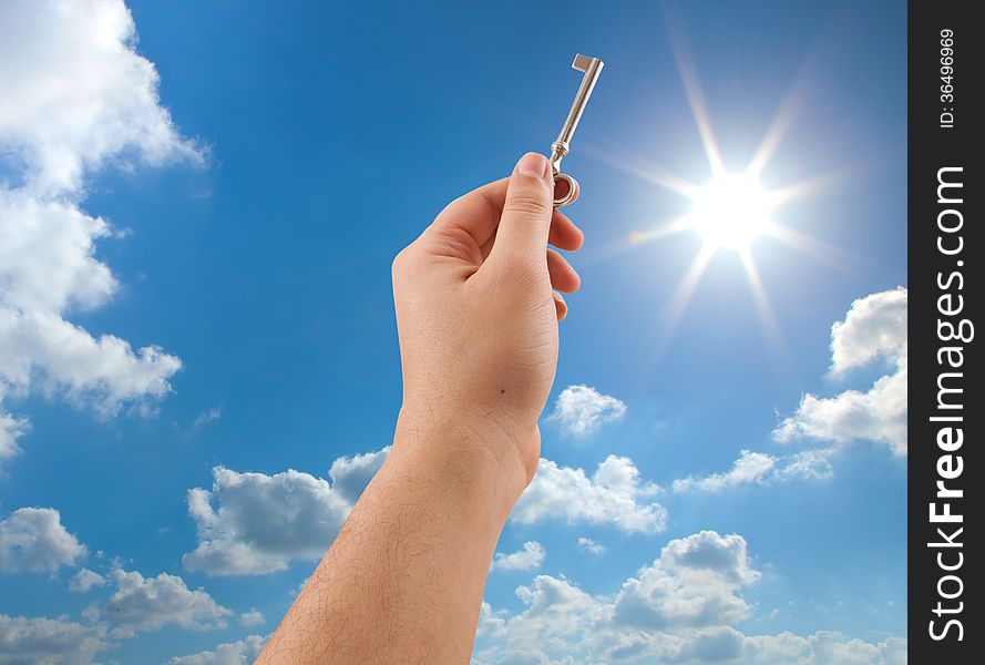 Hand holding key on sunny sky background. Hand holding key on sunny sky background