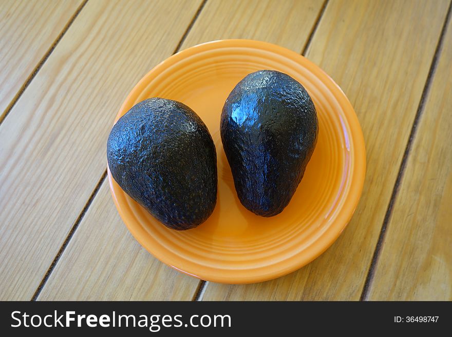 A picture of two avocado on a small plate. A picture of two avocado on a small plate.