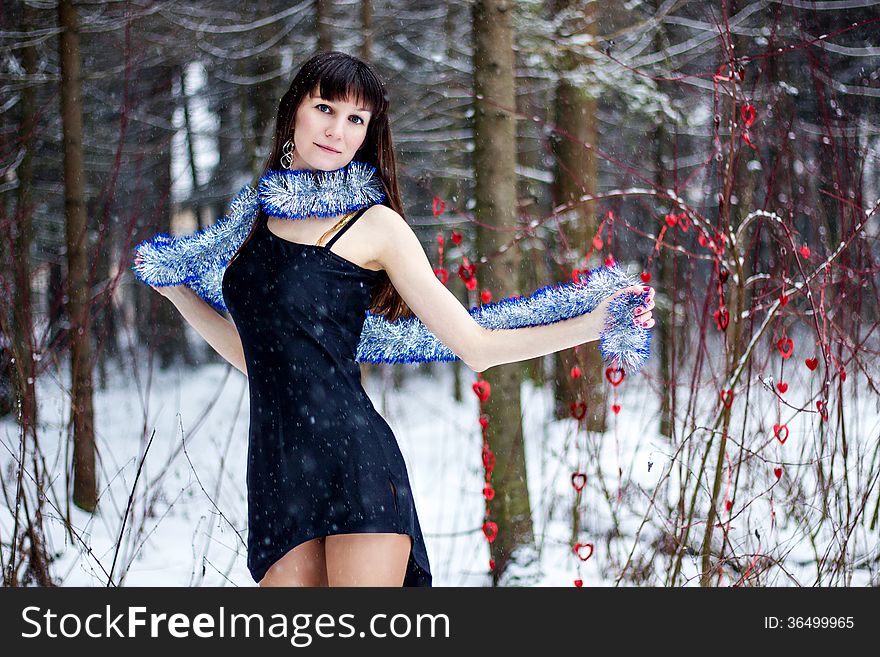 Beautiful woman with bright tinsel in winter forest