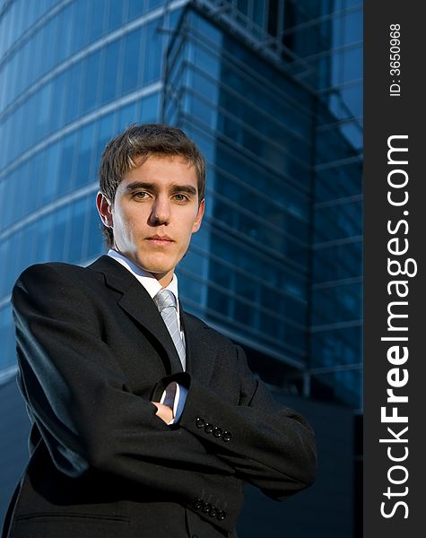 Young confident business man posing in front of office building