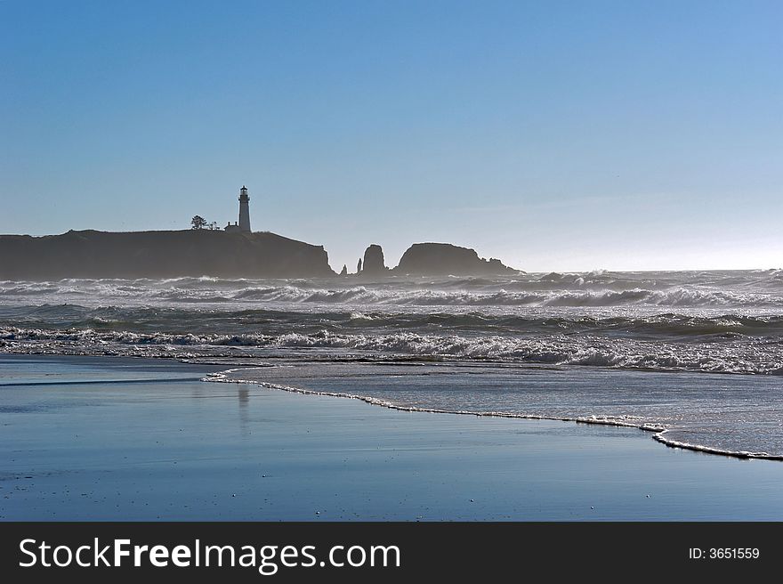 A lighthouse stands tall on the cliff in this timeless image of the amreican west coast showing the waves crashing on the beach and mist in the background. A lighthouse stands tall on the cliff in this timeless image of the amreican west coast showing the waves crashing on the beach and mist in the background