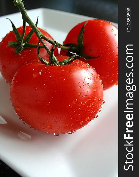 Three fresh tomatoes on white plate
