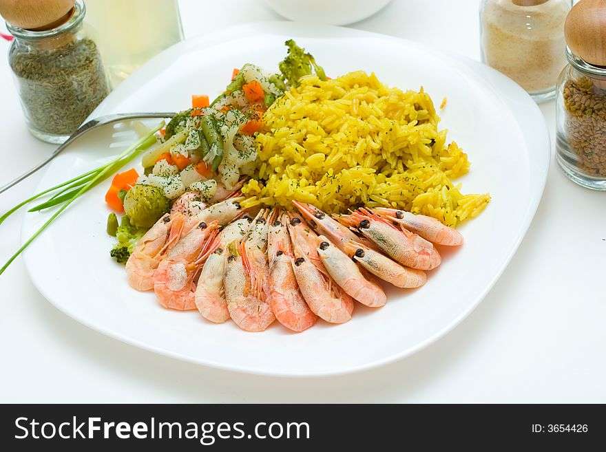 Tasty rice, shrimps and vegetables on the white plate. Eastern cuisine