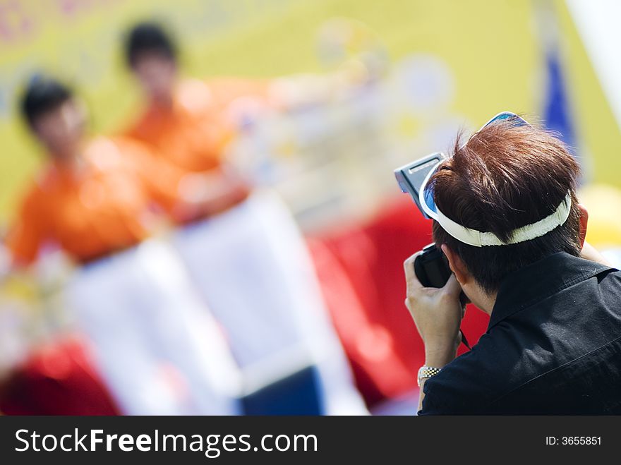 A photographer taking pictures of some dancers on stage. A photographer taking pictures of some dancers on stage