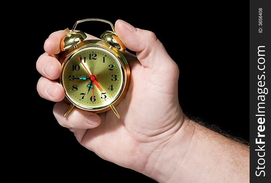 Alarm clock in a hand. Black background. The concept of time.