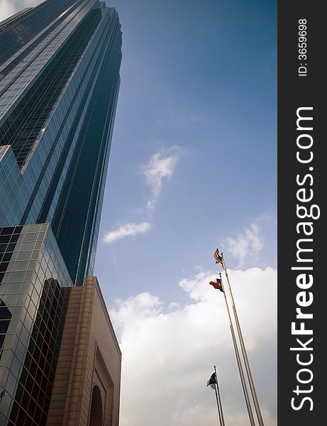 The side of an enormous skyscraper with flags in front flapping in the wind.