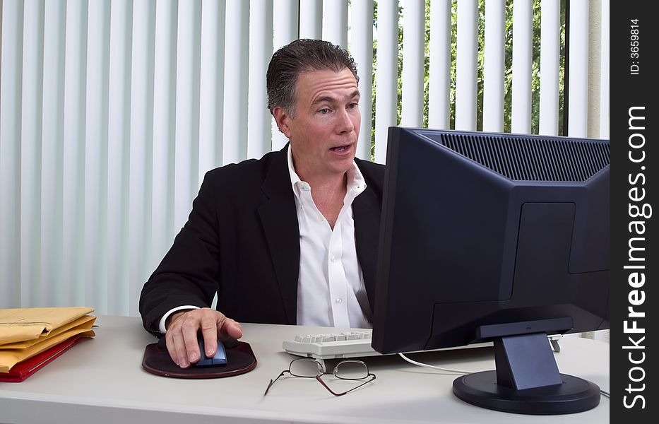 A man sitting in front of a computer with a very surprised expression on his face. A man sitting in front of a computer with a very surprised expression on his face.