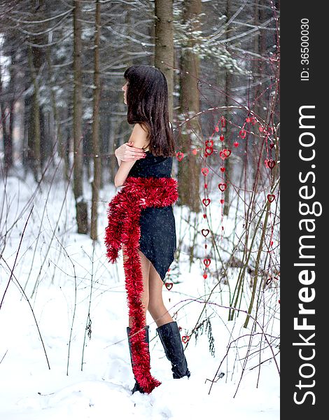 Beautiful woman with bright tinsel in winter forest