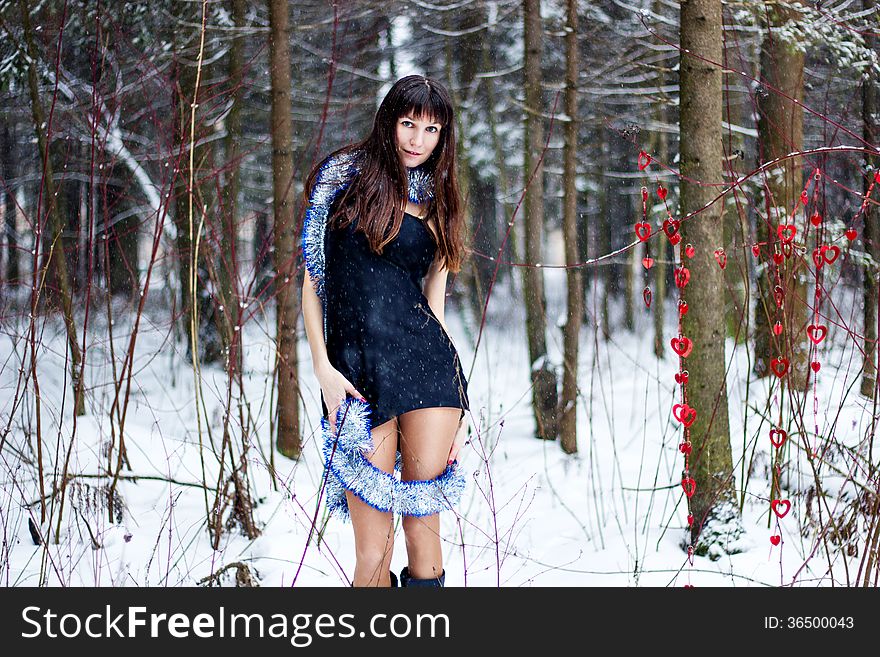 Beautiful woman with bright tinsel in winter forest