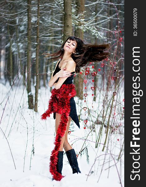 Beautiful woman with bright tinsel in winter forest