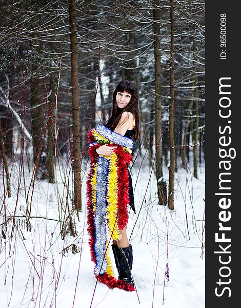 Beautiful woman with bright tinsel in winter forest