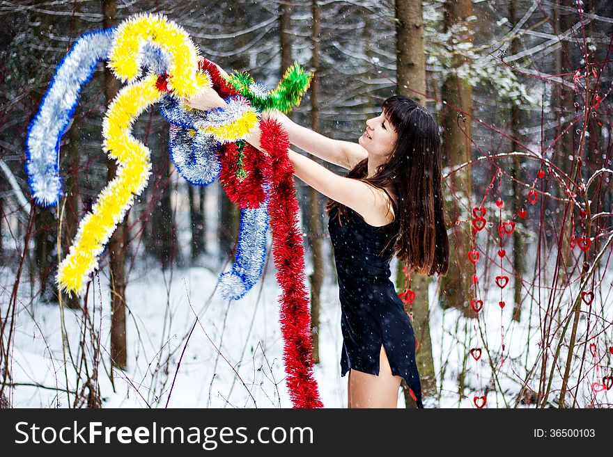 Beautiful woman with bright tinsel in winter forest