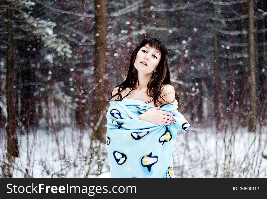 Beautiful woman under warm cute wrap in cold snow forest
