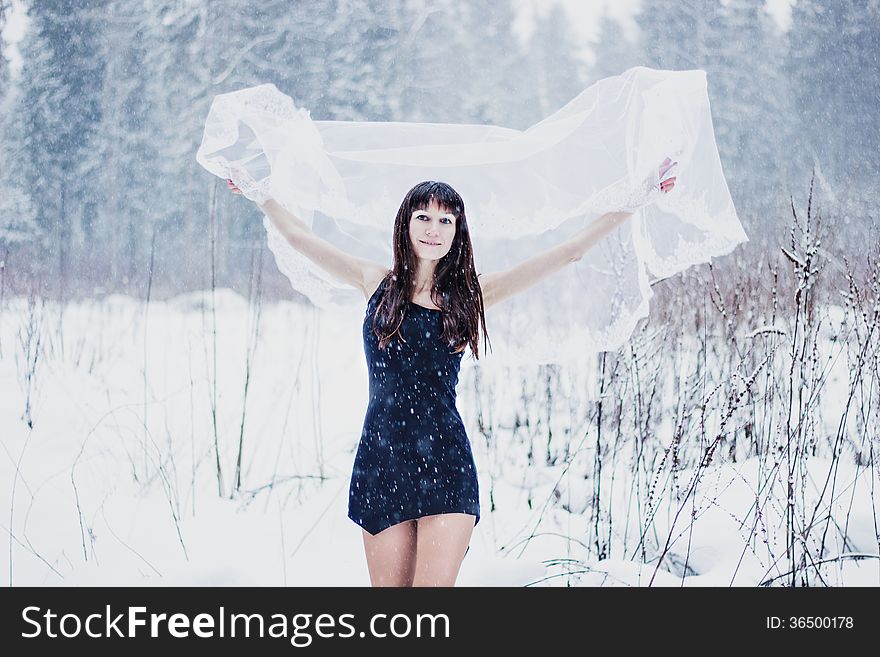 Beautiful bride under veil on white snow background