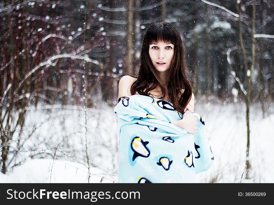 Beautiful woman under warm cute wrap in cold snow forest