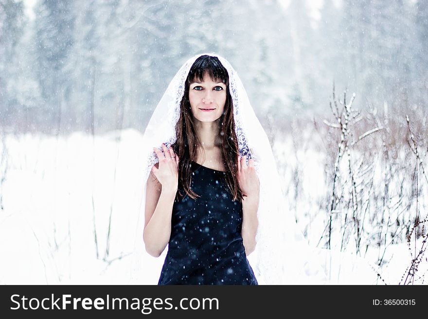 Beautiful bride under veil on white snow background