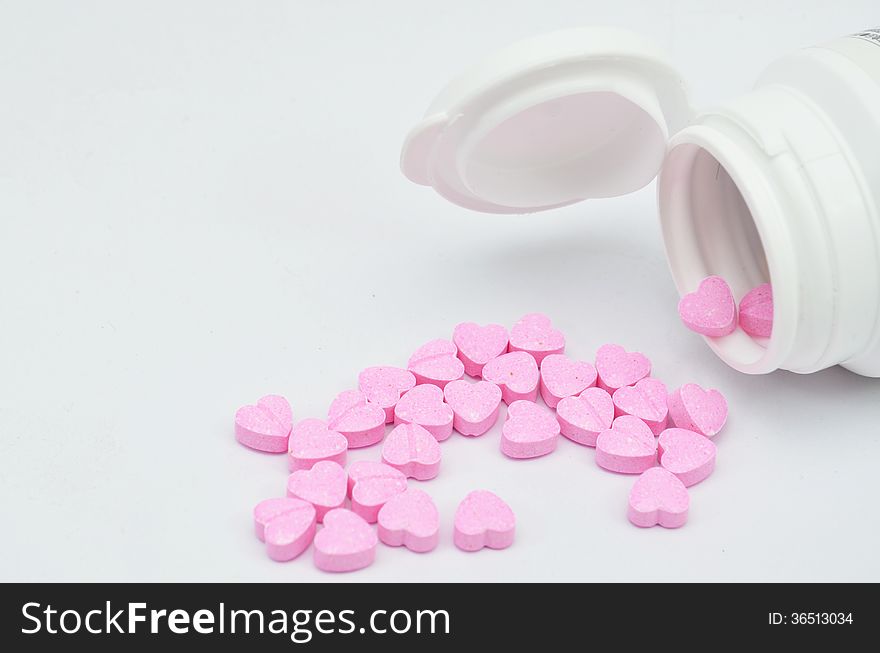 Medicine bottle and heart pills on white background