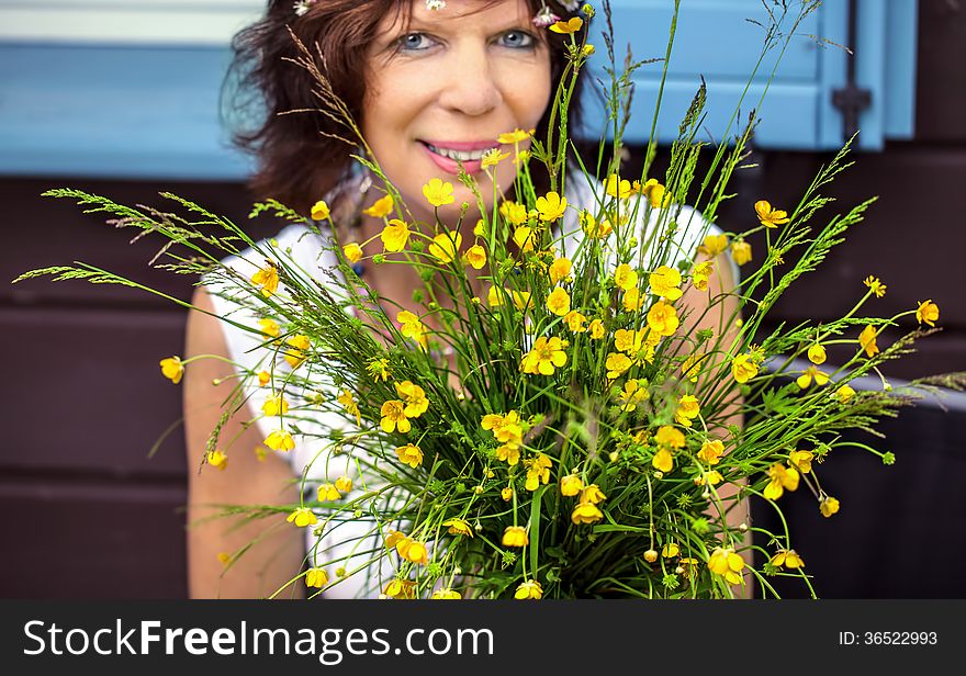 Smiling woman has a nice time behind a bunch of self-picked buttercups. Smiling woman has a nice time behind a bunch of self-picked buttercups