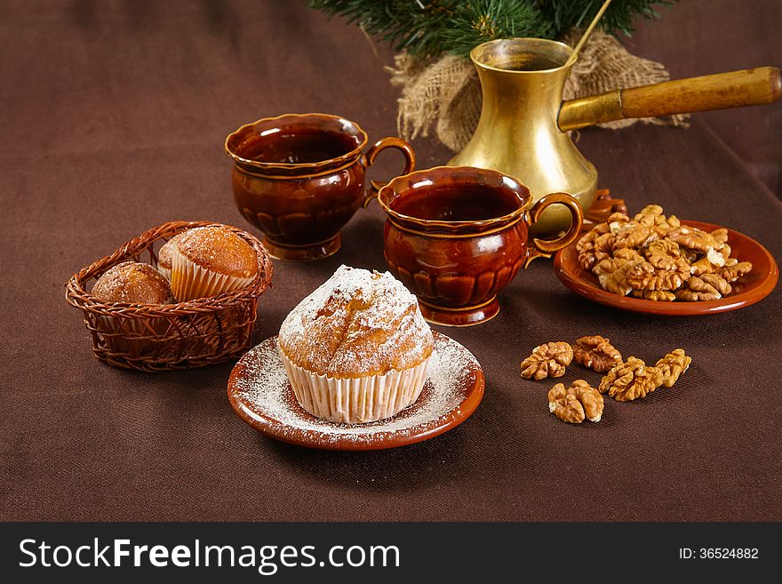 Fresh muffins on a brown table with a cups of coffee and coffee pot