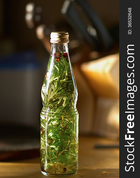 Bottle with herb oil, pepper and garlic on the table. Bottle with herb oil, pepper and garlic on the table