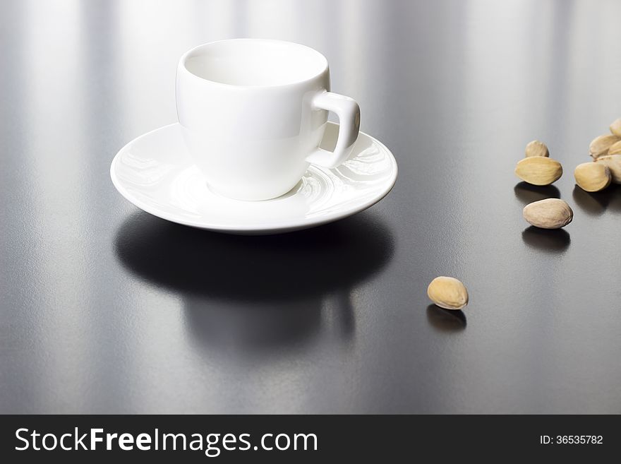 Coffee white cup and plate with nuts on table. Coffee white cup and plate with nuts on table