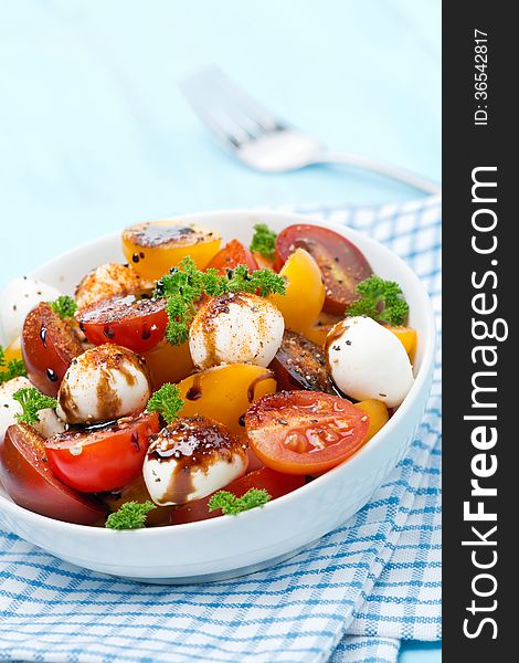 Bowl of salad with mozzarella, balsamic sauce and colorful cherry tomatoes, vertical, close-up. Bowl of salad with mozzarella, balsamic sauce and colorful cherry tomatoes, vertical, close-up