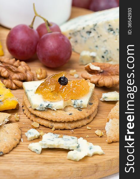 Crackers with blue cheese and apple jam, nuts and grapes, vertical, close-up