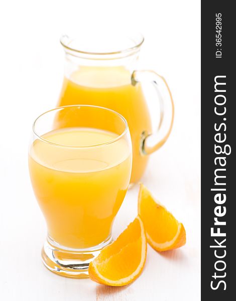 Glass and jug of orange juice and fresh orange slices, vertical