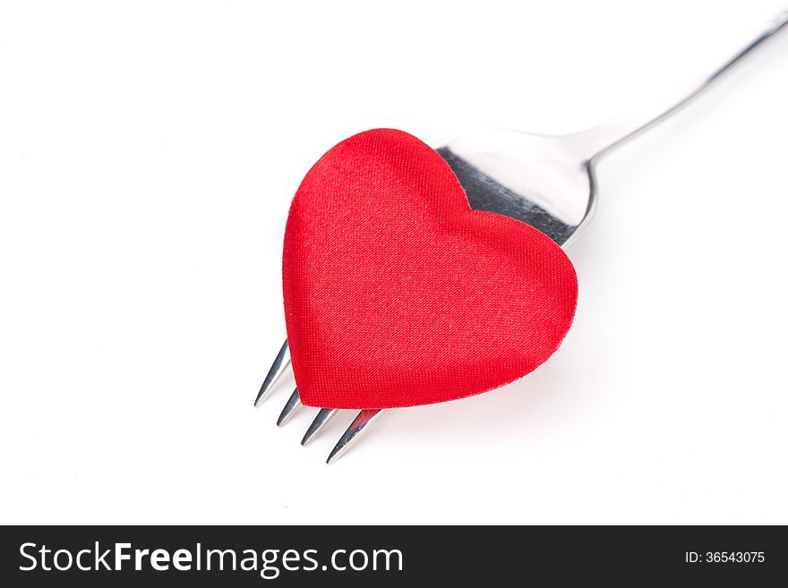 Red heart on a fork, close-up, isolated on white