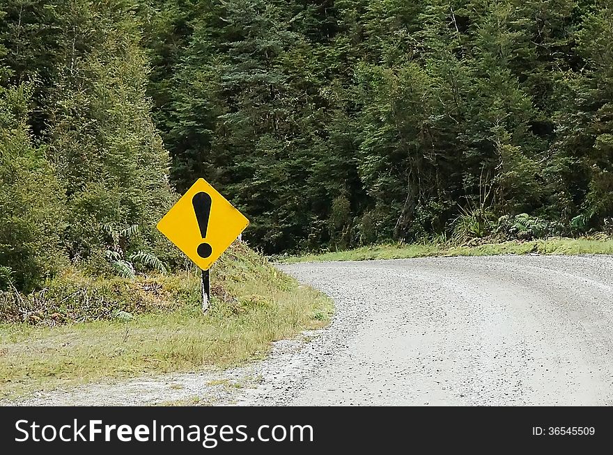 Picture of an exclamation traffic sign on a rough road meaning danger