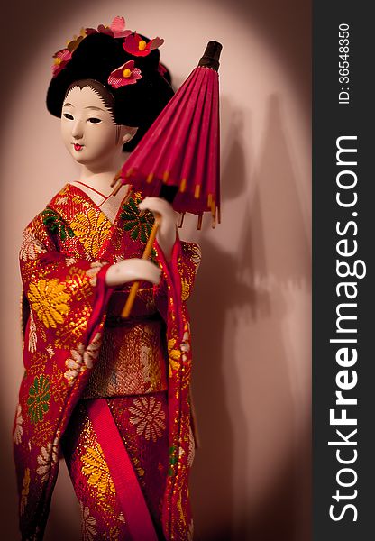 An original Japanese doll with an umbrella and flowers in hairs. An original Japanese doll with an umbrella and flowers in hairs.