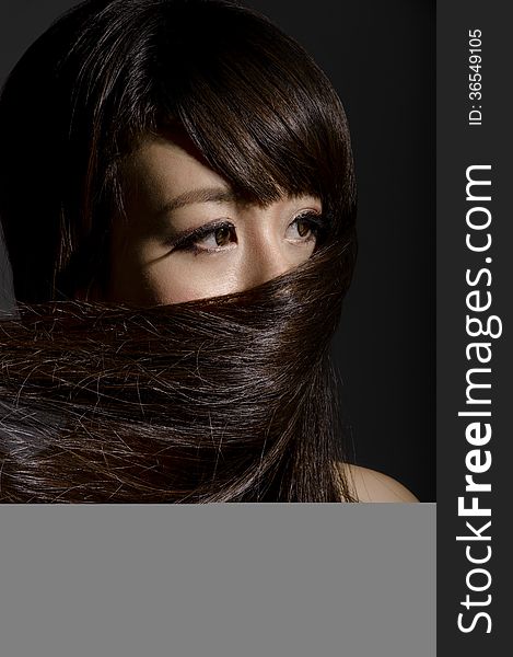 Asian lady masking the lower potion of her face with her own hair. Asian lady masking the lower potion of her face with her own hair.