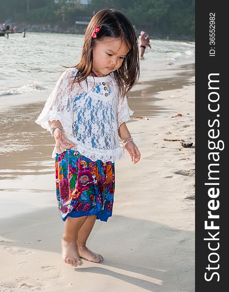 Backview of a caucasian white girl child with long blond hair standing and playing in the water of the Phuket on a beach in Thailand during summer holidays. Backview of a caucasian white girl child with long blond hair standing and playing in the water of the Phuket on a beach in Thailand during summer holidays.