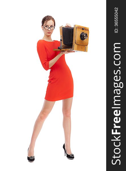 Girl in red dress with an old camera on a white background