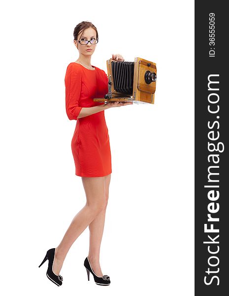 Girl in red dress with an old camera on a white background